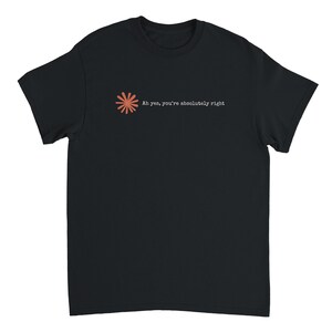 Puede incluir: Una camiseta negra de manga corta con un pequeño icono de estrella de color coral en la zona del pecho izquierdo. Junto al icono, el texto "Ah yes, you're absolutely right" está impreso en blanco con una fuente estilo máquina de escribir.