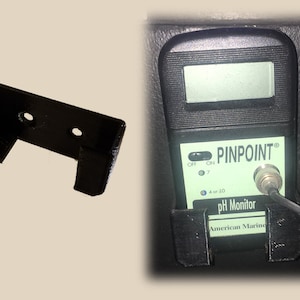 May include: A black plastic wall mount for a pH monitor. The mount has two holes for screws. The monitor is not included.