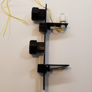 May include: A black plastic water level sensor with three black knobs and a white float. The sensor is mounted on a black plastic base with a yellow wire attached.