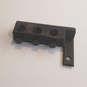 May include: Black plastic 3D printed wall mount with four holes and three knobs.