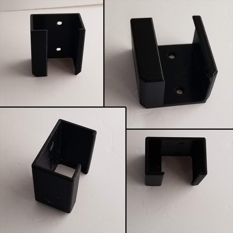 May include: Four black plastic wall mount brackets with a U-shaped opening. The brackets are designed to hold a variety of items, such as shelves, signs, or other decorative elements.