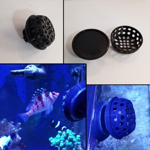 May include: A close-up of a black 3D printed fish tank filter attachment. The filter has a round, porous design with multiple holes. The filter is shown in a fish tank with a blue background and a colorful fish swimming in the tank.