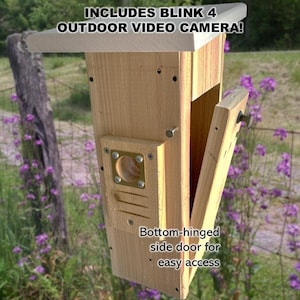 May include: A wooden birdhouse with a side door that opens for easy access. The birdhouse is designed to hold a Blink 4 outdoor video camera. The text "INCLUDES BLINK 4 OUTDOOR VIDEO CAMERA!" is printed on the top of the birdhouse.  "Bottom-hinged side door for easy access" is printed on the side of the birdhouse.