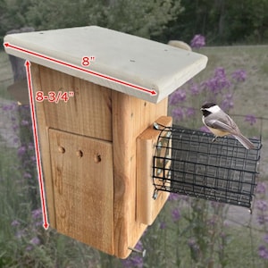 May include: A wooden birdhouse with a light-colored roof and a wire mesh feeder. The birdhouse is approximately 8 inches wide and 8-3/4 inches tall. A small bird perches on the feeder. The birdhouse is made of natural wood.