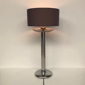 Könnte beinhalten: Moderne Stehlampe mit verchromtem Metallsockel und -stiel. Die Lampe hat einen dunkelgrauen Lampenschirm und einen kleinen, runden, goldfarbenen Akzent. Die Lampe ist etwa 152 cm hoch.