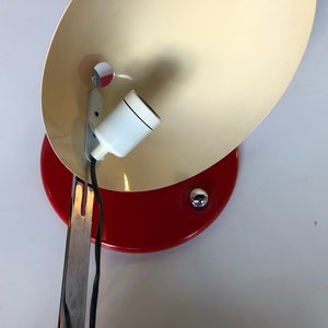 May include: A red and white vintage desk lamp with a metal arm and a white ceramic light socket.