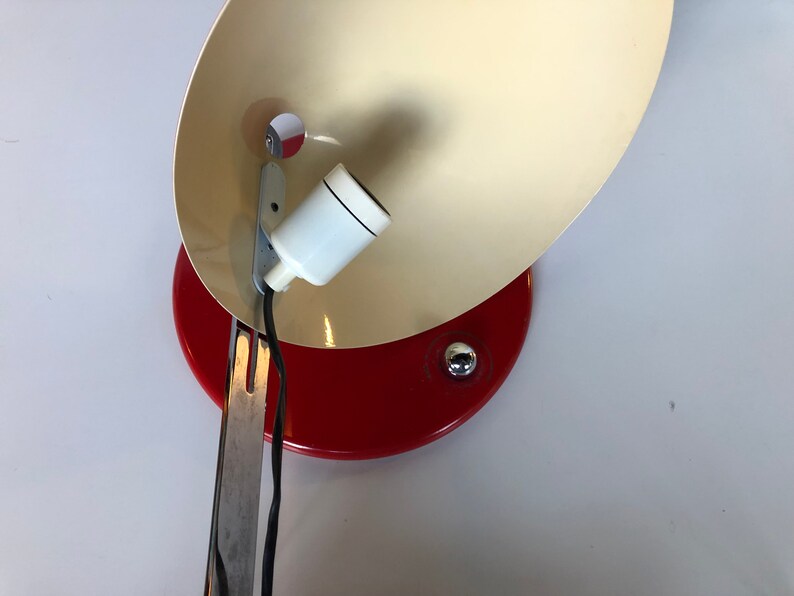 May include: A red and white vintage desk lamp with a metal arm and a white ceramic light socket.