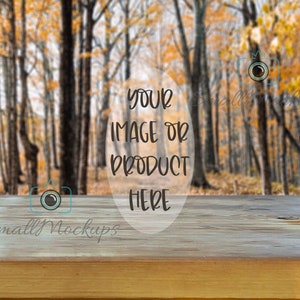 Könnte beinhalten: Eine Holztischplatte mit einem verschwommenen Hintergrund eines Herbstwaldes. Der Text "YOUR IMAGE OR PRODUCT HERE" ist auf den Tisch gelegt.