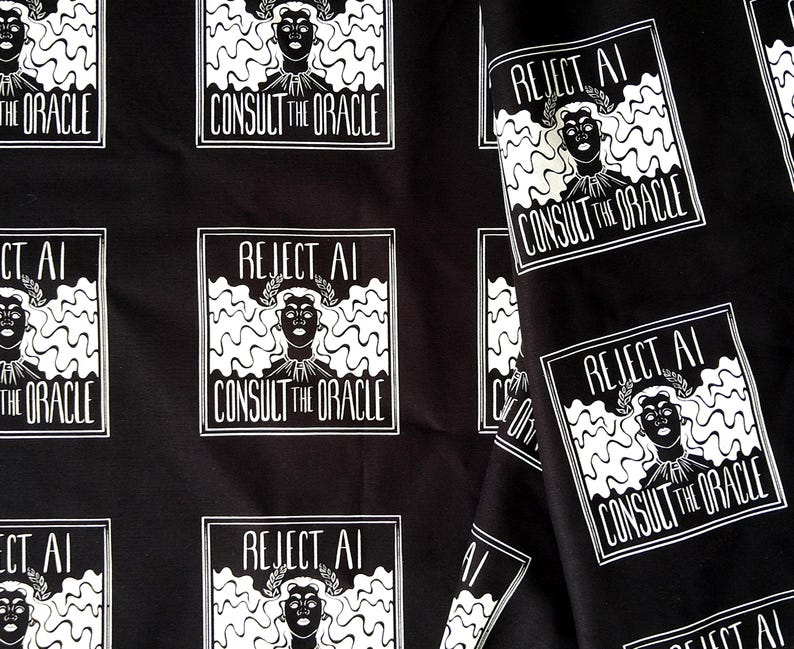 May include: Black fabric featuring a repeating white graphic print of a person with wavy hair wearing a laurel wreath. The text REJECT AI CONSULT THE ORACLE is printed in a rectangular frame around the figure, creating a consistent pattern.