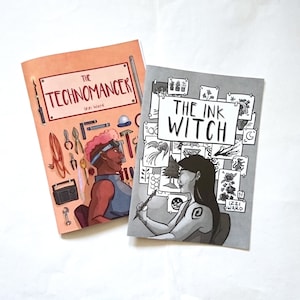 May include: Two comic books with pink and grey covers. The book on the left is titled "The Technomancer" by Izzi Ward. The book on the right is titled "The Ink Witch" by Izzi Ward.