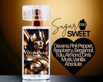 May include: A clear perfume bottle with a gold and rose gold top. The label features a Wonder Woman graphic and the word "Wonderous". The bottle is 1 fl. oz. and includes a list of fragrance notes.