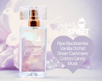 May include: A clear perfume bottle with a gold-colored top and a transparent cap. The label reads "Cashmere Clouds" with a cloud design. The scent notes are listed as ripe blackberries, vanilla orchid, sheer cashmere, cotton candy, and musk. The bottle contains 30ml (1 fl oz).