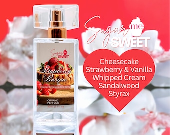 May include: A clear perfume bottle with a gold-colored sprayer and a label featuring a strawberry dessert. The label reads "Strawberry Basque" and "Organic Perfume 30ml (1 Fl. oz)." The bottle is set against a red background with white floral accents.