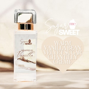 May include: A clear perfume bottle with a gold cap and the words "Wrapped in Vanilla" on the label. The label also includes the text "Organic Perfume" and "30ml 1 fl oz". The background features the words "Sugar me SWEET".