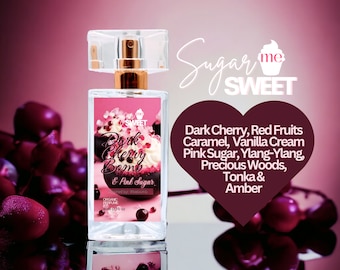 May include: A perfume bottle with a clear rectangular design, featuring a pink label with the text "Dark Cherry Bomb & Pink Sugar." The label includes a cupcake graphic and a list of fragrance notes. The bottle is topped with a gold-colored sprayer and a clear cap.