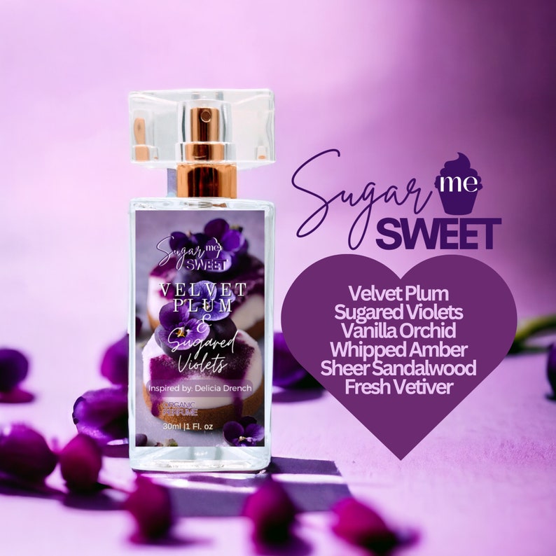 May include: A clear perfume bottle with a gold-colored sprayer and a clear cap. The label reads "Sugar Me Sweet" and "Velvet Plum & Sugared Violets." The scent notes are listed on a purple heart-shaped graphic.