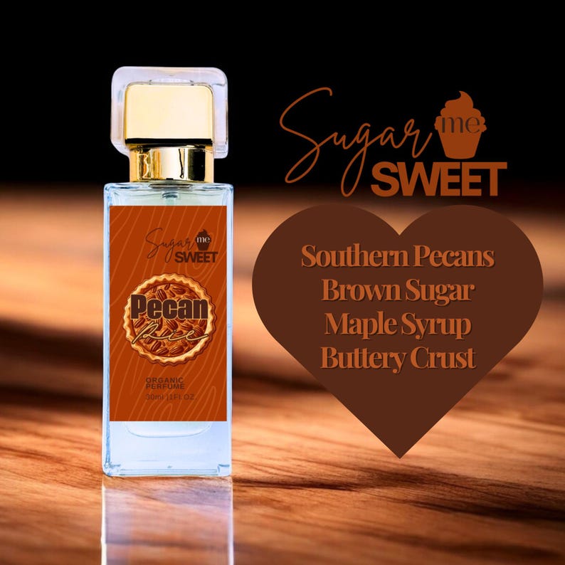 May include: A rectangular perfume bottle with a gold cap and a brown label featuring the text "Pecan Pie" and "Sugar Me Sweet." The label also lists "Organic Perfume" and the volume. A heart-shaped graphic lists ingredients: Southern Pecans, Brown Sugar, Maple Syrup, and Buttery Crust.