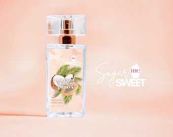 May include: A clear glass perfume bottle with a gold-coloured atomizer and a clear cap. The label features a coconut and papaya illustration with the text "coconut milk & papaya" and "organic perfume". The brand name "Sugar me Sweet" is also visible.