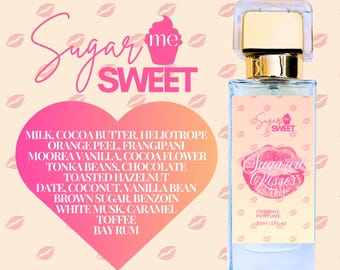Puede incluir: Un frasco de perfume con tapa dorada y cuerpo transparente y rectangular. La etiqueta dice "Sugared Kisses" y "Organic Perfume". Los ingredientes están listados en un gráfico en forma de corazón, incluyendo leche, manteca de cacao y vainilla.