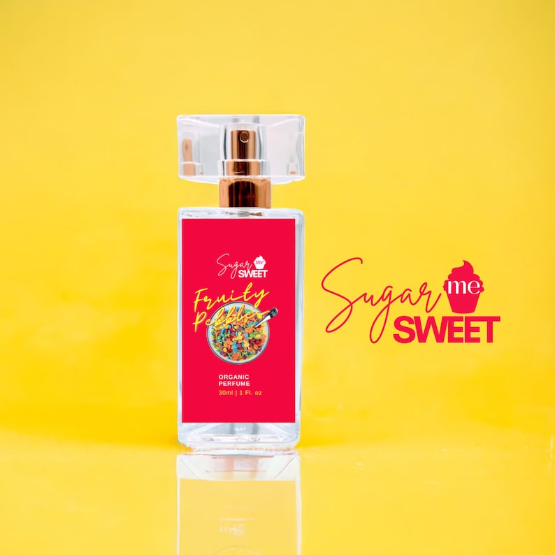 May include: A clear perfume bottle with a red label featuring the text "Sugar Me Sweet" and "Fruity Pebbles." The label also includes a colorful cereal graphic and the words "Organic Perfume." The bottle is 1 fl. oz. and has a clear cap.
