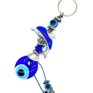 May include: Blue and silver dolphin keychain with a blue evil eye charm and a smaller blue evil eye charm dangling from the bottom.