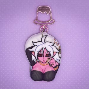 May include: A white and pink anime character with long white hair and black eyes is eating a cookie. The character is wearing a black top and a gold necklace. The character is on a white background with a pink and gold keychain attached to the top.