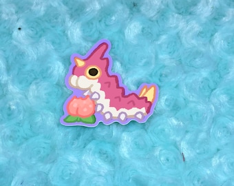 May include: A pink and white cartoon caterpillar with a yellow horn and a pink flower in its mouth. The caterpillar is on a light blue background.