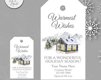 May include: A printable gift tag featuring a watercolor illustration of a cozy cottage with snow-covered mountains in the background. The text reads "Warmest Wishes" and "For a Wonderful Holiday Season!" with space for personalization.