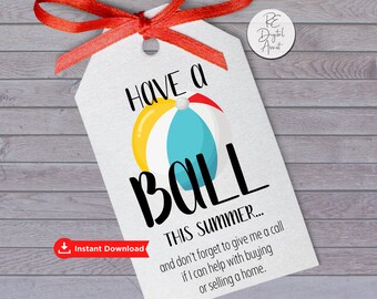 May include: A white printable gift tag with a red ribbon. The tag has a beach ball graphic and the text "Have a Ball This Summer... and don't forget to give me a call if I can help with buying or selling a home."