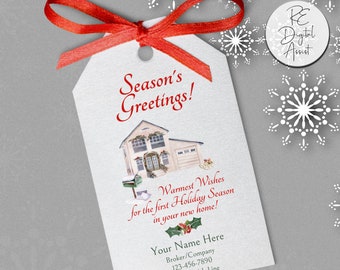 May include: A white gift tag with a red ribbon tied around it. The tag features a watercolor illustration of a house with a wreath on the door and a mailbox. The text on the tag reads "Season's Greetings!" and "Warmest Wishes for the first Holiday Season in your new home!"  The tag also includes the text "Your Name Here", "Broker/Company", a phone number, and "Optional 4th Line".