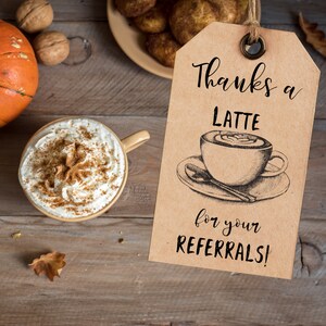 May include: A brown paper gift tag with the text "Thanks a Latte for your Referrals!" and a hand-drawn illustration of a cup of coffee with a swirl of cream on top.