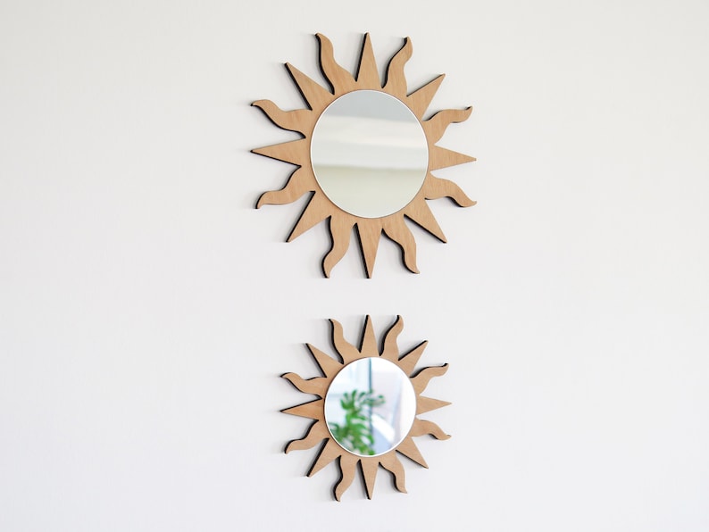 K&ouml;nnte beinhalten: Zwei sonnenf&ouml;rmige Spiegel aus Holz mit einer reflektierenden Oberfl&auml;che. Der gr&ouml;&szlig;ere Spiegel befindet sich oben und der kleinere Spiegel darunter.