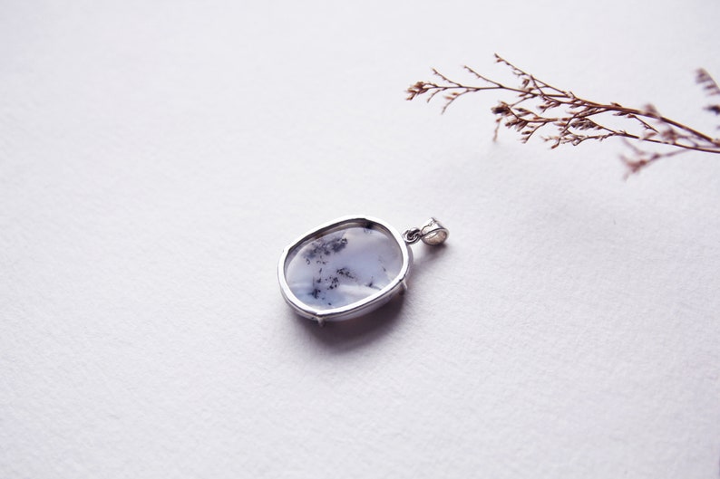 May include: A silver pendant with a white and black dendritic agate stone.