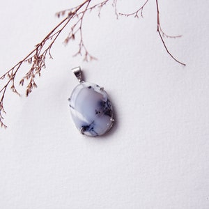 May include: A silver pendant featuring a white and gray oval-shaped gemstone with a silver setting.