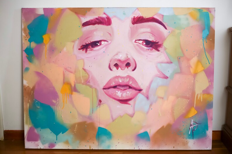 Puede incluir: Una pintura abstracta colorida que presenta un primer plano de la cara de una mujer. La cara est&aacute; pintada en tonos de rosa y blanco, con un efecto de enfoque suave. El fondo es una mezcla vibrante de turquesa, amarillo y rosa.