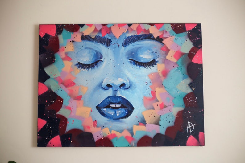 May include: A blue and white painting of a woman's face with closed eyes. The background is a colorful abstract design with pink, blue, and yellow shapes.