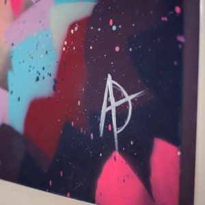 May include: Abstract painting with a colorful background of pink, blue, and red. The painting is signed with a white "A" in the lower right corner.