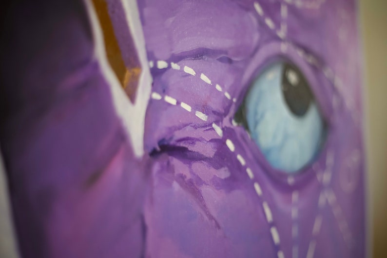 Puede incluir: Primer plano de un ojo pintado de morado con un contorno cosido blanco y un iris azul. El ojo es parte de una pintura m&aacute;s grande.