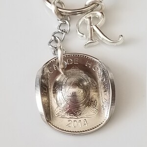 Peut inclure: Porte-clés argenté avec une pièce de 2014 portant l'inscription "REPUBLICA DE HONDURAS" et un charm en forme de lettre "R". Le porte-clés comprend un anneau fendu et une petite chaîne.