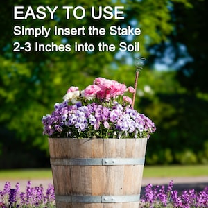 May include: A wooden planter with a metal band around the top, filled with pink and purple flowers. The text "EASY TO USE" is at the top of the image, and the text "Simply Insert the Stake 2-3 Inches into the Soil" is below it.