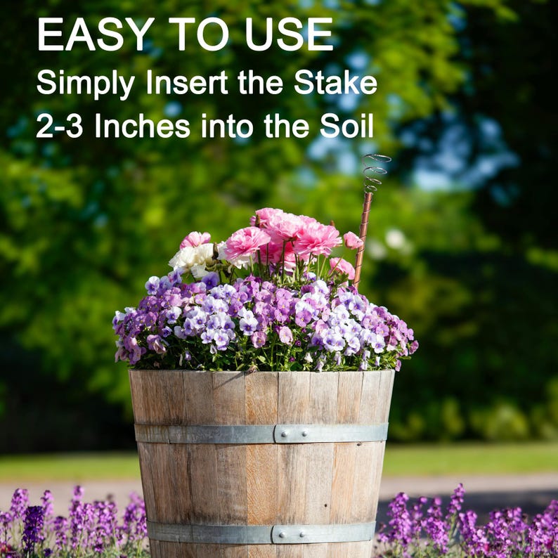 May include: A wooden planter with a metal band around the top, filled with pink and purple flowers. The text "EASY TO USE" is at the top of the image, and the text "Simply Insert the Stake 2-3 Inches into the Soil" is below it.