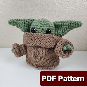 May include: A green crocheted amigurumi toy with large black eyes wearing a brown knitted sweater. The toy is a popular character from the Star Wars franchise. The image includes the text "PDF Pattern".