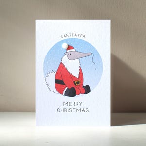 Biglietto d'auguri natalizio personalizzato illustrato "Santeater" in formato A6, con personaggio di Babbo Natale e formichiere, ispirato al gioco di parole di Animixtures - Benefici per l'ente benefico