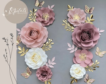 May include: A set of paper flowers in shades of pink and white with gold accents. The flowers are arranged in a symmetrical pattern on a gray background. The flowers are made of paper and have a delicate, layered look. There are also gold leaves and butterflies scattered around the flowers.