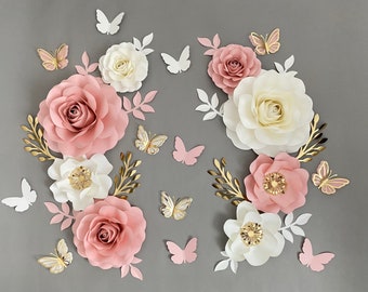 May include: A decorative wall arrangement featuring paper flowers in shades of pink and white, with gold accents. Butterflies in various colors are scattered throughout the arrangement.