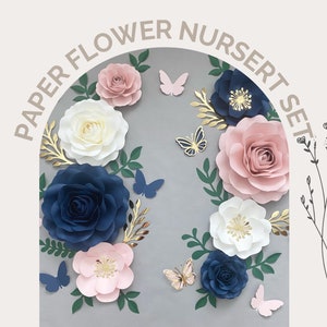 Puede incluir: Un conjunto de decoraci&oacute;n de guarder&iacute;a de flores de papel con grandes flores de papel azul marino, blanco y rosa con detalles dorados. El conjunto tambi&eacute;n incluye varias mariposas peque&ntilde;as en rosa y azul.