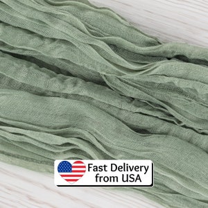 May include: Sage green fabric with a crinkled texture. The fabric is draped and appears to be lightweight. The image includes a text box with the text "Fast Delivery from USA" and an American flag heart.