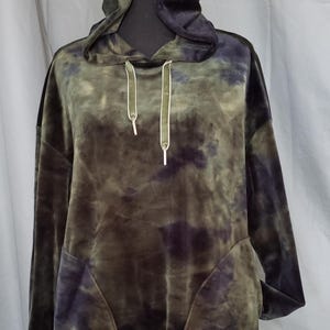 Pode incluir: Um moletom verde e roxo tie-dye com capuz com cord&atilde;o e bolso frontal. O moletom de manga comprida &eacute; feito de um material macio e aveludado. O moletom com capuz &eacute; exibido em um manequim preto.
