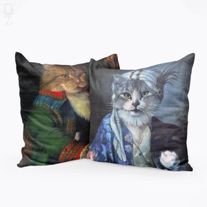 May include: Two decorative throw pillows featuring cats dressed in historical attire. One pillow features a cat in a green military uniform with a white fur collar. The other pillow features a cat in a blue and white patterned robe with a white turban and a feather.