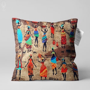 Può includere: Un cuscino decorativo con un design colorato di ispirazione africana che presenta donne in abiti tradizionali che portano cesti e brocche. Lo sfondo è una tela color beige con silhouette di alberi e animali. Il testo "Africa" è stampato sul fondo del cuscino.